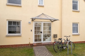 Ein Gebäude mit Glastür, einer kleinen Veranda und einem draußen abgestellten Fahrrad.