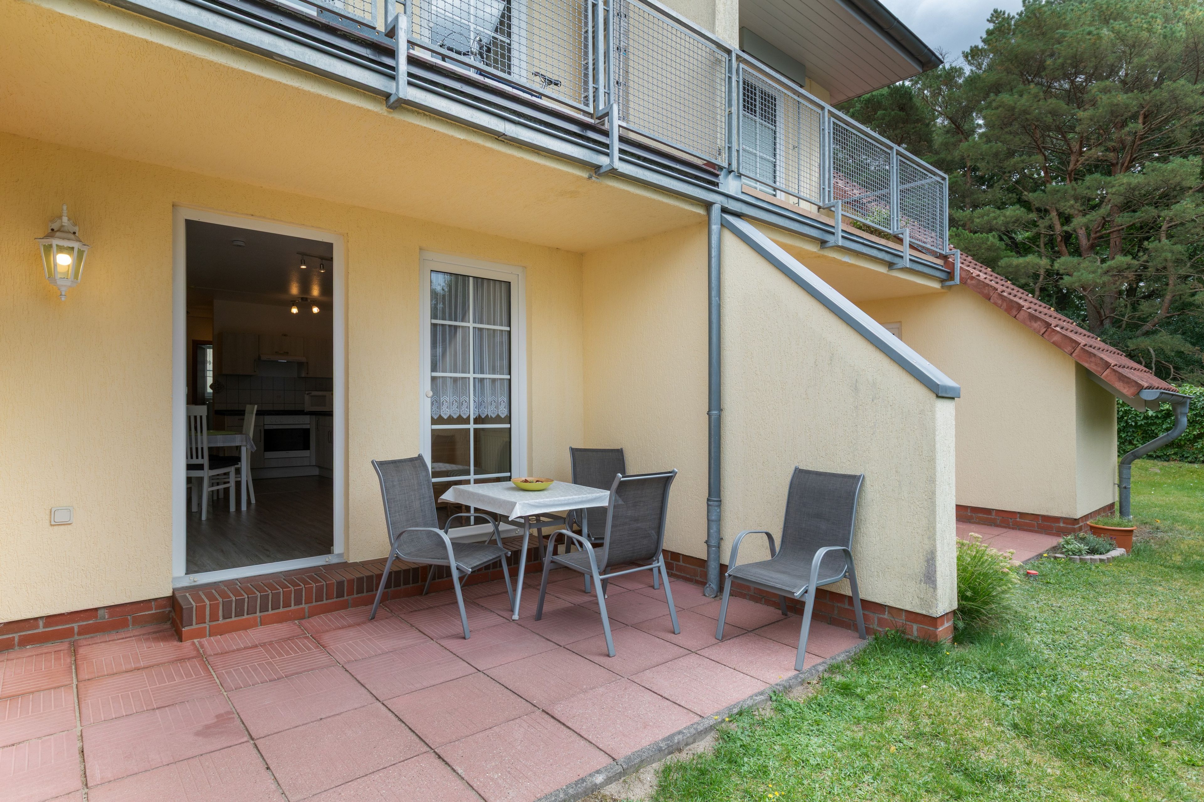 Eine Terrasse mit Tisch und Stühlen, eine Glasschiebetür und ein kleiner Außenbereich mit Küche.