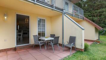 Eine Terrasse mit Tisch und Stühlen, eine Glasschiebetür und ein kleiner Außenbereich mit Küche.