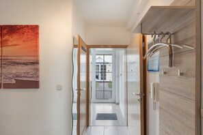 A hallway with a door leading to a balcony, a calendar, and a telephone. - Holiday Apartment with Infrared Sauna & Garden – All Year Round (Karlshagen)