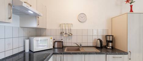 A kitchen with a microwave, toaster, kettle, and coffee maker on the counter.