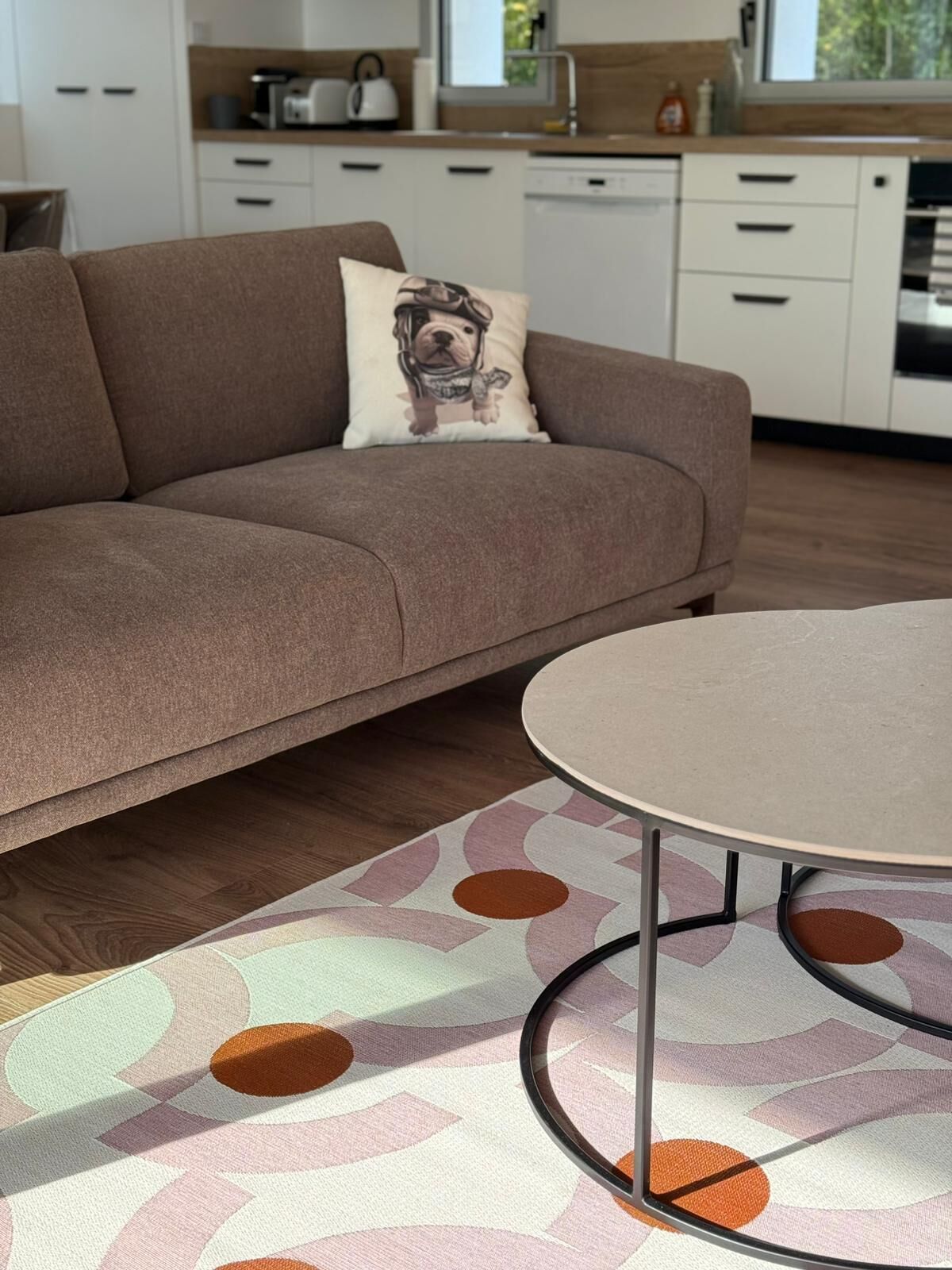Ein modernes Wohnzimmer mit einer Couch, einem runden Tisch und einem gemusterten Teppich.