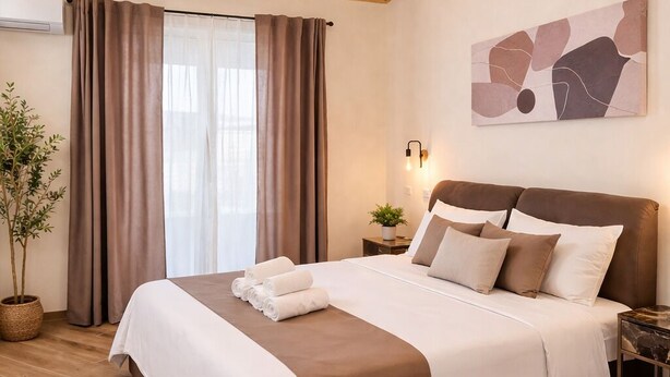 A bedroom with a wooden ceiling, a bed with white and brown bedding, a potted plant, and a wall-mounted abstract art piece. - Sicily Luxury Suites (Palermo)