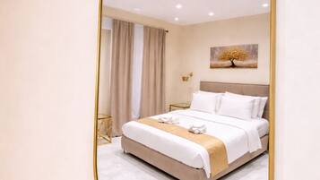 A bedroom with a bed, a bedside table, a lamp, and a wall-mounted mirror.