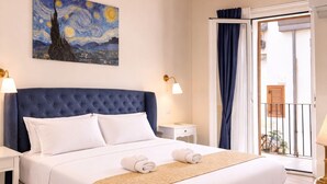 A bedroom with a bed, a painting, a nightstand, a lamp, a window with curtains, and a balcony. - Sicily Luxury Suites (Palermo)