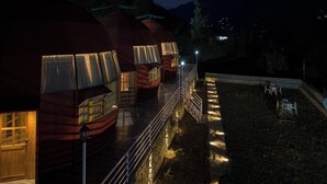 Filetta di cabine a forma di cupola con illuminazione esterna, un viale lastricato e una piccola area salotto all'aperto.