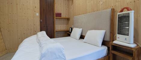 A wooden room with a bed, a heater, and a door.