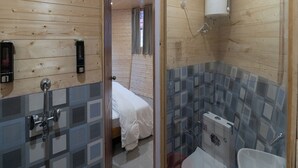 Una stanza con rivestimenti in legno, una doccia, un letto e un bagno con piastrelle.