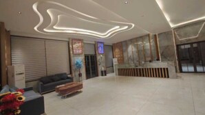 A spacious lobby with a reception desk, a sofa, and a decorative plant. - Hotel Surbhi Khatu Shyam (Danta Ramgarh)
