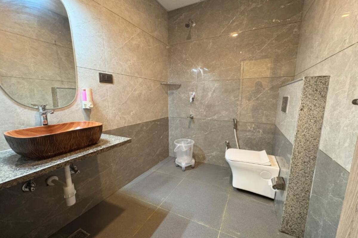 Un baño moderno con tocador de madera, inodoro y zona de ducha.