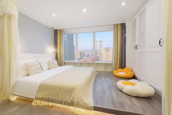 A modern bedroom with a large bed, a window with a city view, a window seat, and a wardrobe. - Qingni No. 8 Hotel Apartment (Dalian)