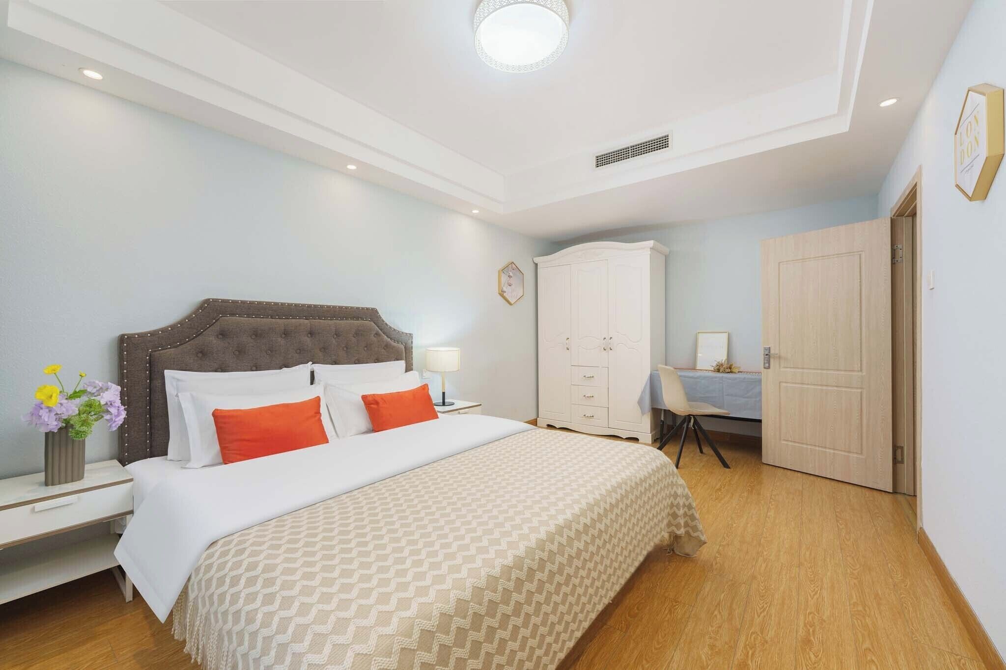 A bedroom with a bed, bedside table, lamp, and a wardrobe.