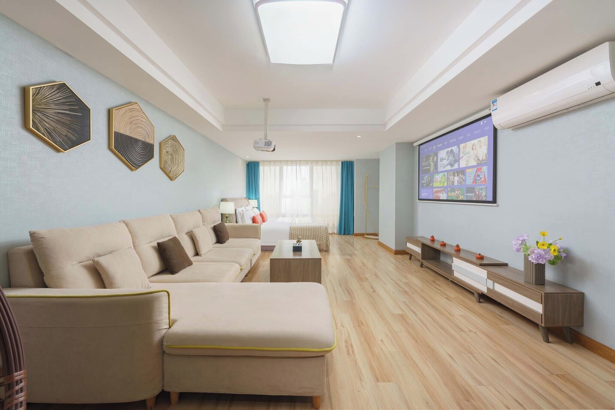 A modern living room with a sectional sofa, a coffee table, a TV, and a projector screen.