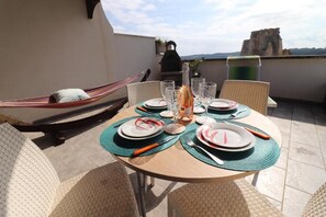 A round table set for four with plates, cutlery, and glasses, a hammock, and a view of the landscape. - Casa Azzurra Torre Dell Orso Stunning Sea View, AC & Free Wifi (Melendugno)