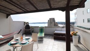Una terraza en la azotea con una mesa lista para comer, una hamaca y vistas al mar.