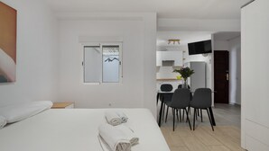 Moderni hotellihuone, jossa on sänky, työpöytä ja ruokailutila.