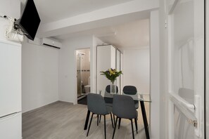 Una habitación moderna con una mesa de comedor, sillas, un televisor de pantalla plana montado en la pared y un equipo de aire acondicionado.