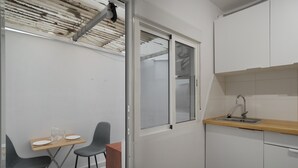 Pieni, käytännöllinen keittiö, jossa on ikkuna, pesuallas sekä ruokailutila, jossa on tuoleja ja pöytä.