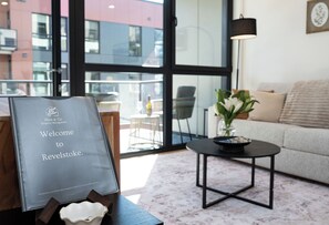 A reception area with a welcome sign, a potted plant, a sofa, and a table. - Salish Peaks - a contemporary one bedroom condo in a brand-new complex (Revelstoke)
