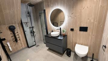 Une salle de bain moderne avec un mur en bois, un miroir rond, un lavabo et des toilettes.