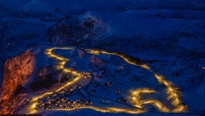 An aerial view of a snow-covered area with illuminated buildings and roads.