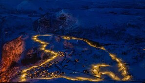 An aerial view of a snow-covered area with illuminated buildings and roads.