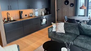 A modern kitchen with dark cabinets, a wooden countertop, and a built-in oven.