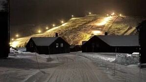 A snow-covered landscape with buildings and a lit ski slope.