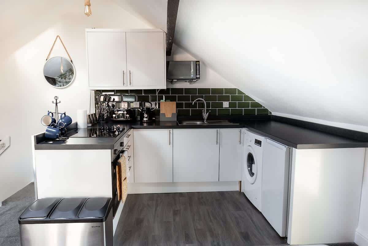 A compact kitchen with a washing machine, a microwave, and a sink.