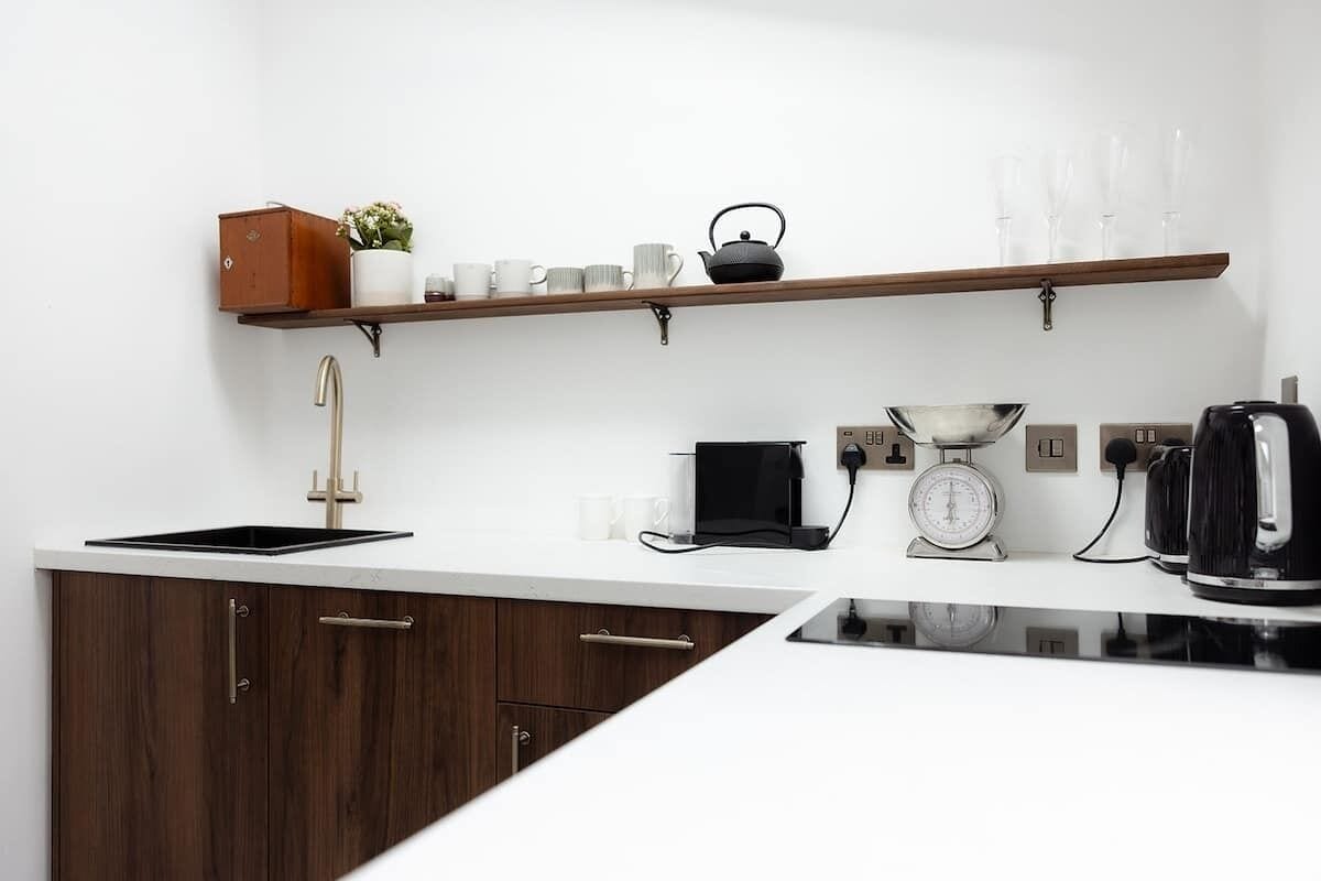 A modern kitchen with a built-in stove, a coffee maker, a scale, and a kettle on the countertop.