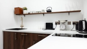 A modern kitchen with a built-in stove, a coffee maker, a scale, and a kettle on the countertop.