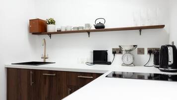 A modern kitchen with a built-in stove, a coffee maker, a scale, and a kettle on the countertop.