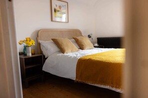 Ein Schlafzimmer mit Bett, Nachttisch, Lampe und einem gerahmten Bild an der Wand.