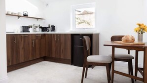 A compact kitchen with wooden cabinets, a refrigerator, a coffee maker, and a window with a view.