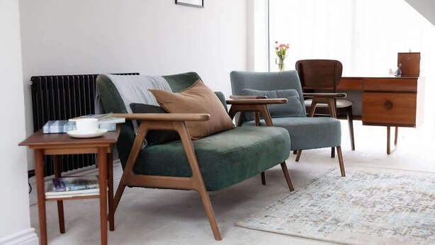 A modern living room with a sofa, armchair, side table, and a wooden dresser.