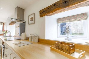 A kitchen with a wooden countertop, a stove, a window with a polka dot valance, and a wooden crate labeled 'FARM FRESH EGGS'. - Cosy Farm Cottage with Hot Tub & Countryside Views (West Yorkshire)