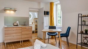 Una cocina compacta con una estufa moderna, un comedor con mesa y sillas, y vistas a un baño a través de una puerta abierta.