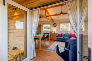 Ein gemütliches Zimmer mit Holzbalkendecke, einer Billardkugel, einem Sofa und einem Essbereich.