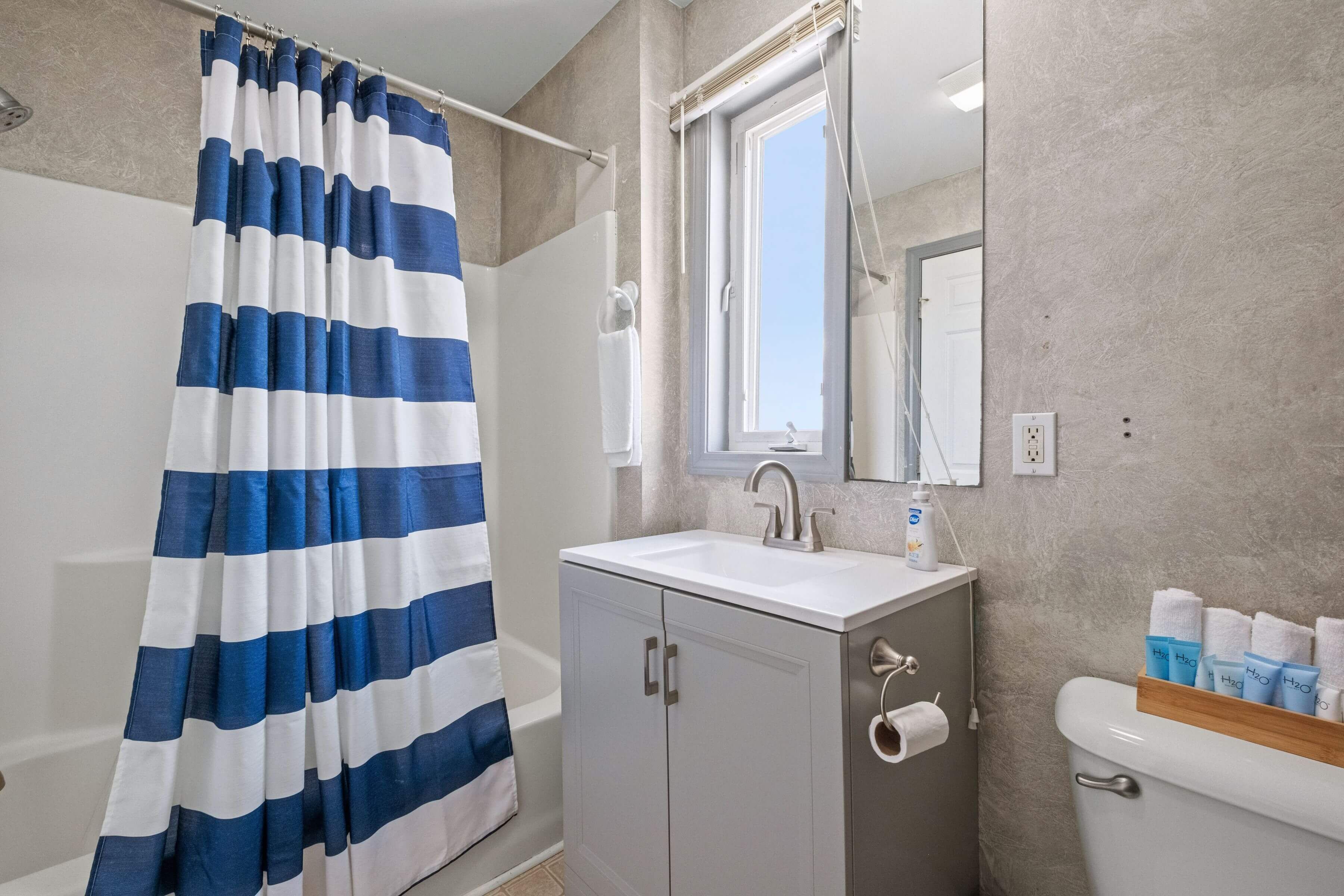 A bathroom with a shower curtain, a sink, a toilet, and a mirror.