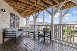 A covered porch with wooden beams, a sofa, a chair, and a table. - Ocean Air Suites 300 Feet from Beach, Strip (Hampton)