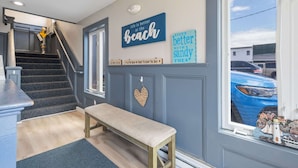 Una scala conduce a un pianerottolo con una panchina, un muro con insegne decorative e vista su un'auto blu all'esterno.