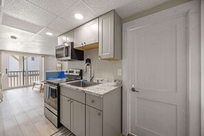 A modern kitchen with stainless steel appliances, a granite countertop, and a sliding glass door leading to a balcony. - Ocean Air Suites 300 Feet from Beach, Strip (Hampton)