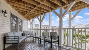 A covered porch with wooden beams, a sofa, a chair, and a table. - Ocean Air Suites 300 Feet from Beach, Strip (Hampton)