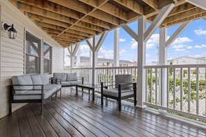 A covered porch with wooden beams, a sofa, a chair, and a table. - Ocean Air Suites 300 Feet from Beach, Strip (Hampton)