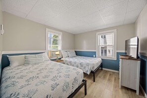 Une chambre avec deux lits, un bureau et une télévision.