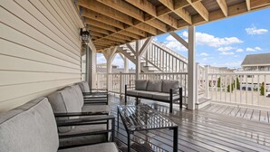 A covered outdoor seating area with wooden beams, a metal table, and grey cushioned sofas. - Ocean Air Suites 300 Feet from Beach, Strip (Hampton)