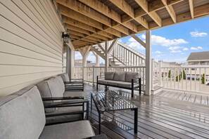 A covered outdoor seating area with wooden beams, a metal table, and grey cushioned sofas. - Ocean Air Suites 300 Feet from Beach, Strip (Hampton)
