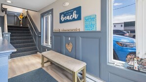 A staircase leading to a landing with a bench, a wall with decorative signs, and a view of a blue car outside. - Ocean Air Suites 300 Feet from Beach, Strip (Hampton)