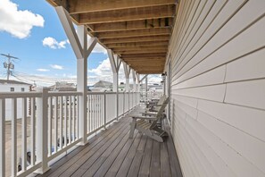 A wooden deck with white railings, a covered area, and a view of buildings in the background. - Ocean Air Suites 300 Feet from Beach, Strip (Hampton)