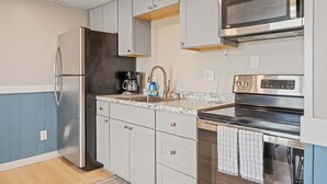 A modern kitchen with stainless steel appliances, white cabinetry, and a granite countertop. - Ocean Air Suites 300 Feet from Beach, Strip (Hampton)